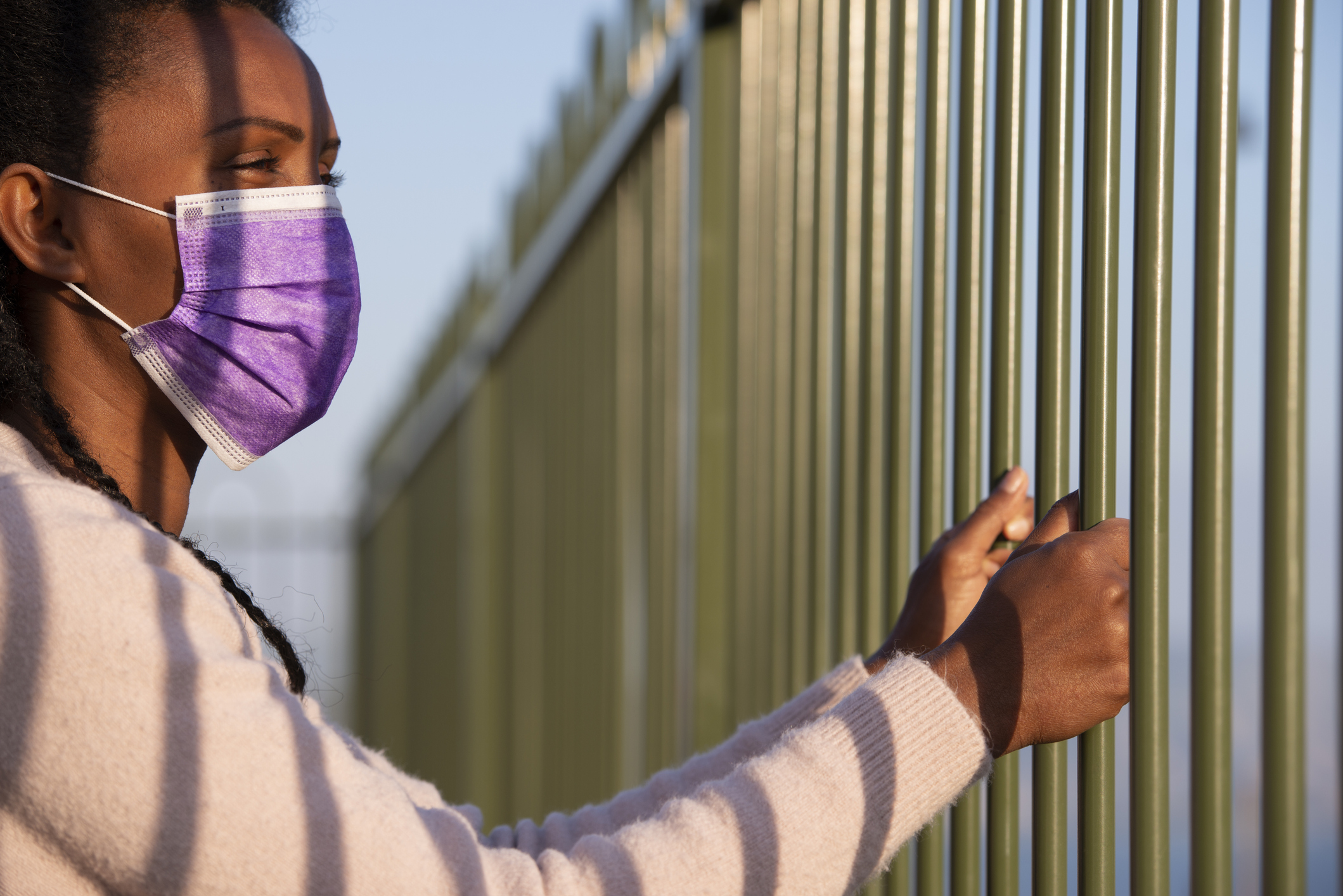 Black woman with mask behind bars